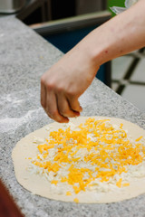 Chief putting ingredients on the top of pizza.