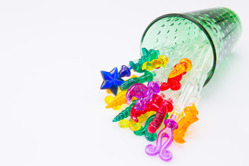 Colorful plastic swizzle sticks spilled from glass on white background