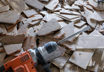 Ein Abbruchhammer liegt auf einem Haufen abgebrochener Fliesen