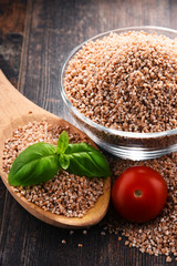 Bowl of uncooked spelt on wooden table