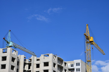 Tall and heavy construction crane towers against a blue sky