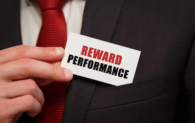 Businessman putting a card with text REWARD PERFORMANCE in the pocket