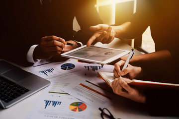 Business people using pen,tablet,notebook and laptop computer are planning a marketing plan to...