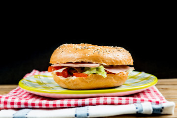 Bagel with fresh cheese and fresh lettuce on table