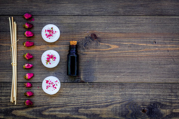 Skin care and relax. Cosmetics and aromatherapy concept. Oil and candles on dark wooden background top view copyspace
