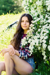 Portrait of a young girl near a bush with white flowers