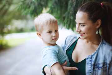 Fototapeta premium Young mother with little son having fun playing in the Park