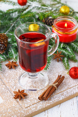 New Year's mulled wine in a glass on the background of twigs, candles and garlands.