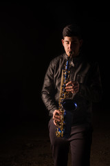 Naklejka premium Man playing saxophone, with black background