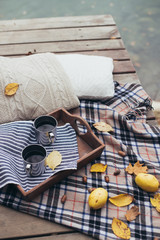 Autumn picnic with two cups on a wooden tray in a forest near lake 