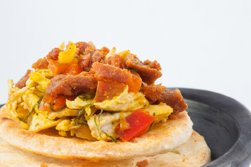 Traditional Colombian arepa topped with chicken breast and pork rind