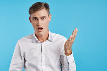 young guy in a white shirt on a light blue background shows emotion