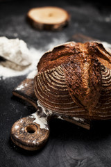 freshly baked bread, flour and tomatoes on a wooden board on a table