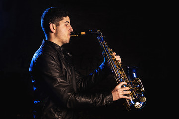 Obraz na płótnie Canvas Man playing saxophone, with black background