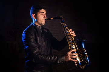 Fototapeta na wymiar Man playing saxophone, with black background