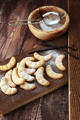 Vanille Kipferl cookies for christmas on brown wooden table with sugar.