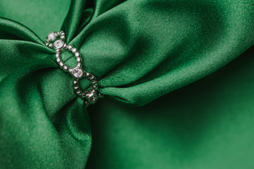 Silver ring and green satin fabric empty copy space background.