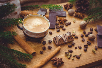 Obraz na płótnie Canvas New Year's winter composition with coffee and spices in the kitchen on a wooden dinette and with pine branches. Beauty and inspiration with winter desserts.