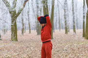 Young man stretching his muscles on a cold winter day before running in forest.