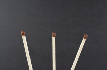 Three matches on a dark grey background