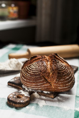 freshly baked bread and flour on a wooden board on a kitchen towel on a table