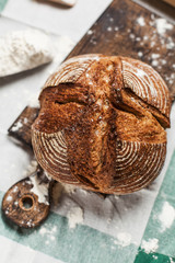 freshly baked bread and flour on a wooden board on a kitchen towel on a table