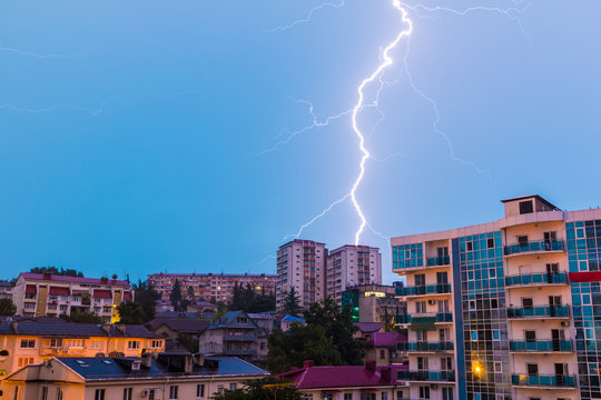 View of apartment buildings on the mountain with lightning during a morning thunderstorm, Sochi, Russia
