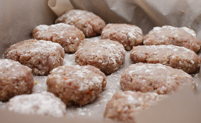 fresh minced raw meat cutlets on tray with flour on parchment