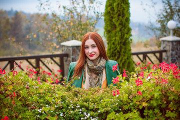 Girl with red hair, dressed in a green leather jacket and scarf casual style, resting in a pleasant place is in a sense of peace and harmony. Beauty in every day and moment, the pleasure of life