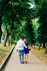 beautiful couple in love with a woman walking in a park on a bench kissing at sunset and loving each other, a blue dress and a white shirt with jeans