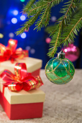 New Year's gifts next to the decorated Christmas tree on a dark blue background with blurred lights. vertical