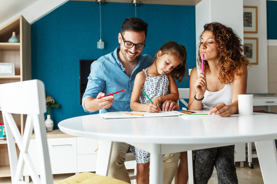 Father and mother teach daughter to draw.They sitting in living room and making fun.