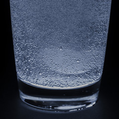 A soluble tablet dropped in a glass of water over dark background