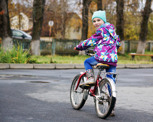 Little girl riding a bicycle in the autumn park