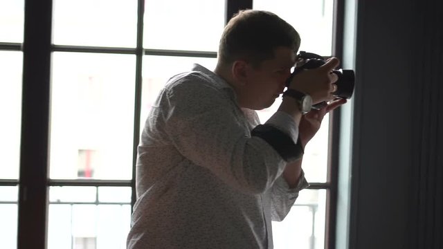 Photographer shoots on his camera near window