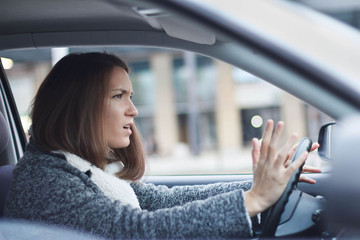 Nervous young business woman driving car in city