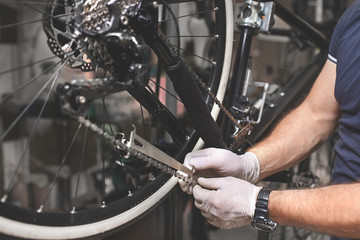 Bicycle mechanic in a workshop in the repair process - obrazy, fototapety, plakaty
