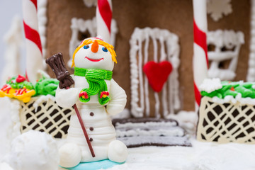 Close up of a snowman from sugar mastic near gingerbread house