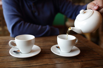Person filling the cup with green tea