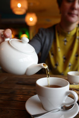 Person filling the cup with tea