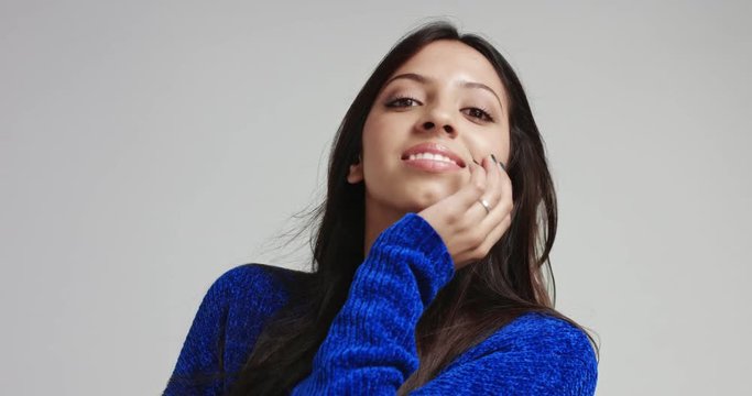 Seductive and dreamy latina girl with long black hair in a thick warm blue sweater moving in slow motion and smiling