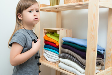 The girl is measuring her mother's clothes and shoes. Order in the closet. Smart storage system. Capsule wardrobe. The girl plays and puts things in order in her mother's things. Wardrobe order.