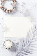 Still life with silver and white Christmas decorations and a blank card