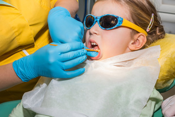 kid in dentist clinic.Dental health. Female dentist curing a child patient in doctor's consulting room. Pediatric dentist. Medical inspection. Health care.dentist examining llittle girl's teeth 