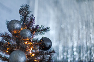 Christmas dark blurred background with a black Christmas tree, ornaments and bokeh lights