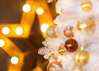 Festive blurred Christmas background with white Christmas tree, Christmas tree ornaments bokeh lights and electric garland