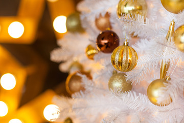 Festive blurred Christmas background with white Christmas tree, Christmas tree ornaments bokeh lights and electric garland