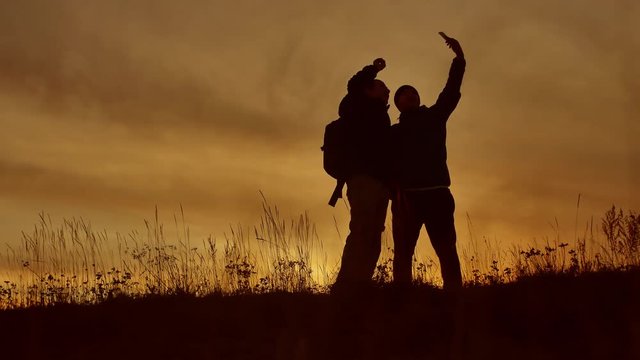 two tourists do selfie at sunset silhouette of sunlight. Travel two people in jackets do selfie lifestyle autumn silhouette