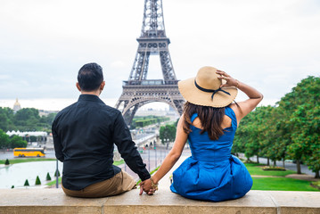 Young couple of tourists sitting in front of Eiffel tower in Paris