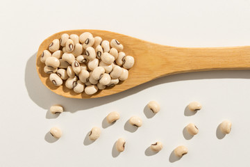 Black Eyed Pea legume. Healthy grains on a wooden spoon. White background.